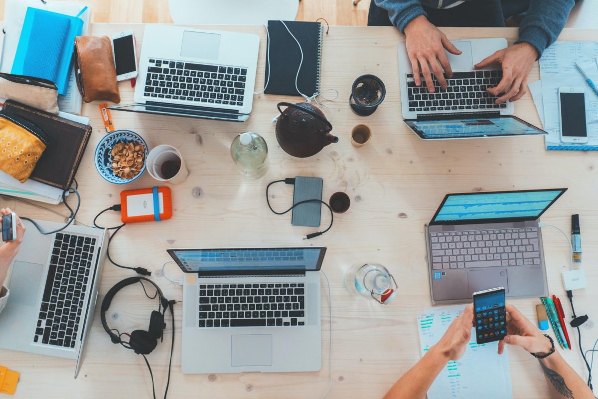 People at work around several laptops and devices.