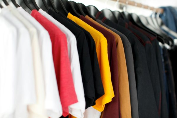 Row of different colored t-shirts on hangers.